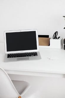 Otwarty laptop leży na białym biurku
